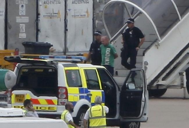 A man suspected of being responsible for a bomb scare aboard a Qatar Airways flight is escorted from the plane by police at Manchester airport. 