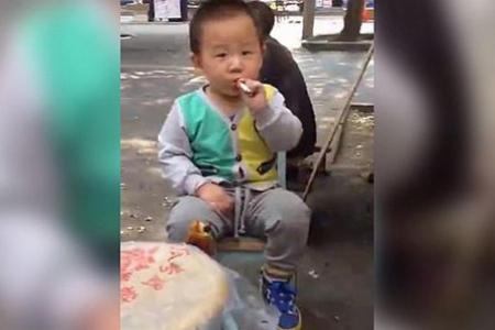 Chinese toddler seen smoking a cigarette while onlookers laugh