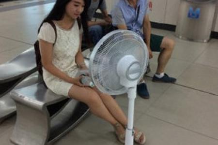 Girl brings fan around on China subway to keep cool