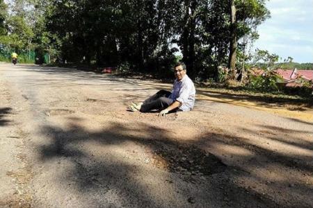 Malaysia MP poses in pothole for protest photo