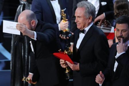 Jordan Horowitz of &quot;La La Land&quot; (L) holds the card announcing &quot;Moonlight&quot; as the winner of the Best Picture Oscar as presenter Warren Beatty (C) and show host Jimmy Kimmel stand behind.