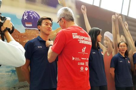 Swimmer Quah Zheng Wen receiving a Singapore flag pin from his father,