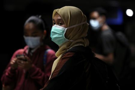 Passengers wearing protective masks wait for a commuter train at a station, following the outbreak of the coronavirus in Kuala Lumpur,