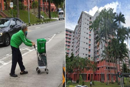 Elderly Grab delivery man with hunchback pushes trolley across the street alone