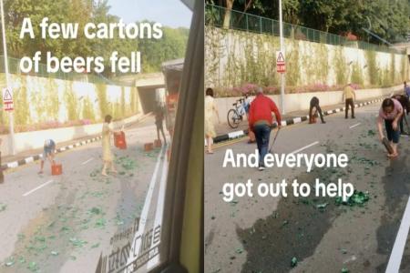 Passers-by get out of cars to help clean mess after lorry spills crates of beer