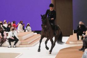 Chanel brand ambassador Charlotte Casiraghi heads down the catwalk on horseback while wearing a Chanel jacket made of black tweed and decorated with sequins.