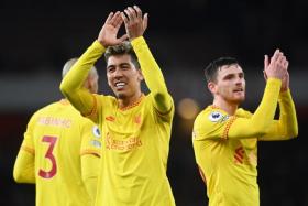 Liverpool forward Roberto Firmino (centre) and teammate Andrew Robertson celebrate after the match.