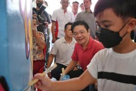 DPM Lawrence Wong observing a young resident as he paints a mural at a void deck on Oct 30, 2022.