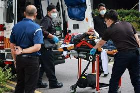 SCDF officers preparing to move an injured person into an ambulance, following an incident involving a stuck gondola at 168 Robinson Road on March 20, 2023.