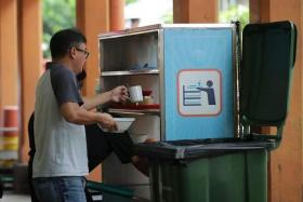 A diner returning used trays and crockery during lunch time at Maxwell Food Centre on June 1, 2023.