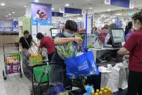 Shoppers at a FairPrice outlet using their own bags for groceries, on July 3, 2023.