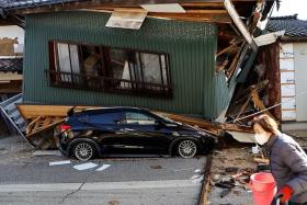 A resident walking past a collapsed house, caused by an earthquake, in Nanao, Ishikawa prefecture, Japan, on Jan 2, 2024.
