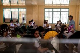 Grade 12 students use hand fans as they attend a class at the Commonwealth High School, in Quezon City, Metro Manila, on April 18.