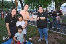 Feng Sheng owner Tong Chun Wee (in black top) giving away chicken rice packs to a family of Swifties at the National Stadium on March 7.