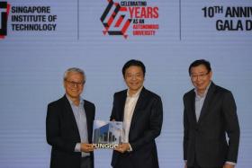 SIT president Chua Kee Chaing (left) presenting a commemorative book, titled SIT: Journey To Punggol, to DPM Lawrence Wong. With them is Mr Bill Chang, chairman of SIT&#039;s board of trustees.