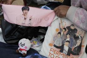A fan shows a scarf with the portrait of BTS&#039; Jin while camping near River Plate&#039;s Monumental stadium in Buenos Aires, on Oct 26, 2022.