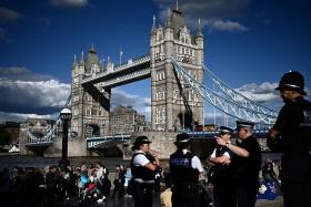 Police officers stand by as people queue near Tower Bridge in London to pay their respects to the late Queen Elizabeth II.