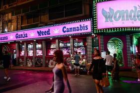 People walking past a cannabis dispensary store in the Sukhumvit area of Bangkok. 
