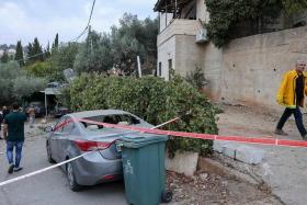 A man walks past a car hit by rockets fired from Gaza in the Arab-Israeli town of Abu Ghosh near Jerusalem on Monday. 