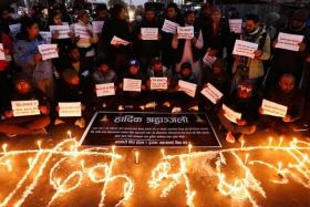 People hold placards as they take part in a condolence and protest meeting following the plane crash of a Yeti Airlines operated aircraft in Pokhara on Jan 15 in Kathmandu, Nepal.