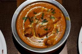 A freshly prepared butter chicken dish is placed on a table inside the Moti Mahal Delux restaurant in New Delhi, India.