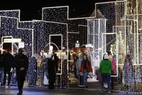 Syrians walk past Christmas decorations at a market in the capital Damascus on Dec 23, 2023.