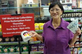 FIRST TIME LUCKY: Madam Betty Goh, a winner of the first week of The New Paper&#039;s World Cup collectible mug lucky draw with the $300 that is part of her prize.