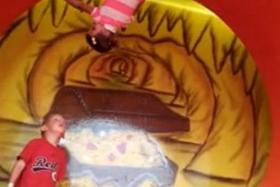 A three-year-old girl hangs upside down after she, not knowingly, gripped tightly onto the side of a spinning barrel ride as she spun 360 degrees before sliding off about 7 seconds later as her feet got closer to the ground. 