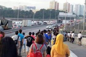 JAMMED UP: (Above) Thousands of commuters had to walk across the Causeway just to get to work in Singapore. 
