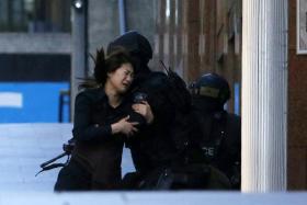 A hostage running towards a police officer outside Sydney cafe, where hostages are being held by a gunman.