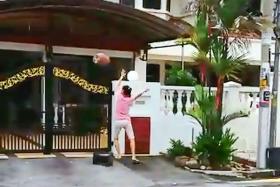A screen grab from the video showing the woman hurling an object onto the driveway of a neighbour’s house.