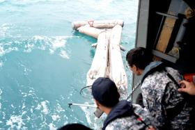 The crew of the RSS Persistence pulling up a life raft found in the sea. 