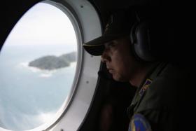 A crew member on an Indonesian Maritime Surveillance looks out the window during a search for AirAsia&#039;s Flight QZ8501.