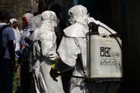 File photo of Red cross workers, wearing protective suits, getting ready for the funeral of an Ebola victim i