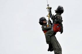 MISSION: (Above) Sgt Goh Zhe-Wen being winched up to a Super Puma helicopter, along with a crew member pretending to be injured and with a mock casualty.