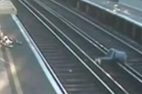 The man loses his footing while trying to cross the railway track.