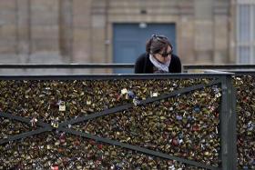A woman looks at padlocks hanging on the Pont des Arts.