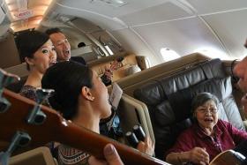 IN-FLIGHT ENTERTAINMENT: (Above, seated) Madam Esther Wee singing along on the flight.