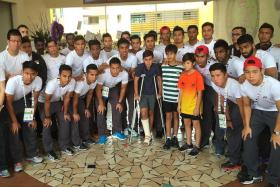 GIVING SUPPORT: The Singapore SEA Games football team during their visit to Tanjong Katong Primary School yesterday afternoon to pay respects to the victims of the Sabah earthquake. With them are Jayden Francis (in crutches), 12, Chaityak Khatwani (in stripes), 12, and Tristan So Kwan Wing (in orange), 12. Jayden was one of the pupils who went on the trip to Sabah with the school.