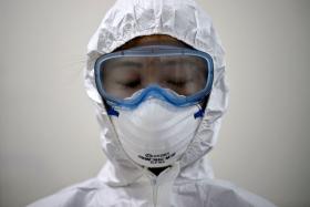 A medical staff member in Seoul, Korea, wearing a protective suit waits to enter an isolation ward for patients with Middle East Respiratory Syndrome (MERS). 