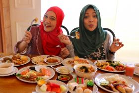 TUCKING IN: Local actresses Mastura Ahmad (left) and Syirah Jusni having lunch at Asian Market Cafe at Fairmont Singapore.