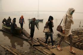 Workers walk up to the shore of a river basin after travelling on a boat as the haze shrouded Batanghari River in Jambi, on Indonesia&#039;s Sumatra island, September 15, 2015