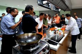 Mr Loo Tiong Bin (right) teaching a class of 18 men how to cook Hainanese pork chop on a weekday evening in a cooking class just for men.