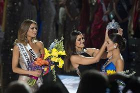 BLUNDER: After host Steve Harvey revealed he had mistakenly announced Miss Colombia Ariadna Gutierrez-Arevalo (in silver gown) as the winner, Miss Universe 2014 Paulina Vega (in black) removes the crown and places it on the head of Miss Philippines Pia Alonzo Wurtzbach (in blue).