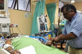 Wilson Ramamoorthy wiping the sweat off his brother Sundaraj, who has been in a coma at the Tengku Ampuan Afzan Hospital's ICU ward after an accident last month.