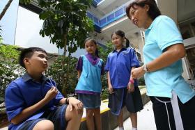 SMART: (Above) Principal of West Spring Primary School, Mrs Jacinta Lim, talking to pupils in their new collared uniform, which was designed by Miss Tiffany Ng and Miss Ho Bao Yiing.