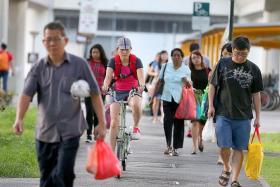 EXPERIMENT: TNP reporter Elizabeth Law (on bicycle) finds the shared path under the MRT tracks in Tampines wide enough for pedestrians and cyclists to share.