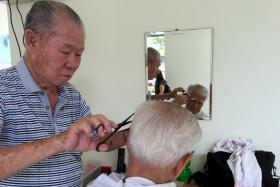Mr Goh Kow Hoon, giving a haircut to a senior citizen at Paya Leber Wellness Centre. He has been volunteering his services as a barber since 2010