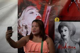 FAN: A Madonna fan in the Philippines taking a selfie in front of a poster of the 57-year-old pop diva, who will perform her second show in Manila today.