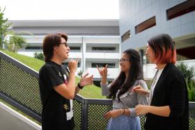 COMMUNICATION: Two of Brendan Lau’s classmates at Millennia Institute, Miss Charisse Agustin (in grey) and Miss Lena Loke (in black), learnt sign language to help them communicate better with him.